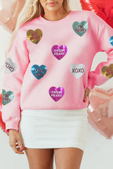 Person wearing a pink sweatshirt with colorful heart-shaped sequins on a white background