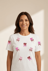 Woman wearing a white t-shirt with pink heart designs on a beige background