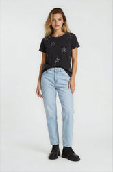 Woman wearing a black t-shirt with star patterns and light blue jeans on a white background