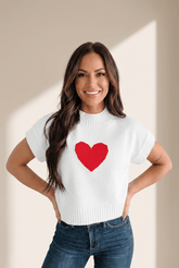 Woman wearing a white sweater with a red heart design on a beige background