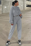 Person wearing a gray tracksuit standing on a concrete pavement.