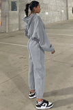 Person wearing a gray tracksuit standing on a concrete pavement.