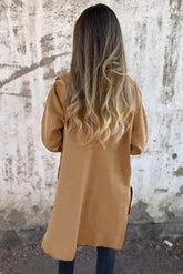 Person wearing a beige coat with a textured wall background