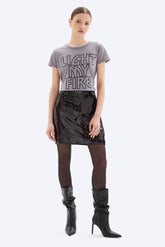 Woman wearing a gray t-shirt with text and a black sequin skirt on a white background