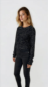 Woman wearing a black sequin top and black pants on a white background