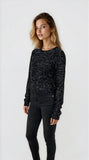 Woman wearing a black sequin top and black pants on a white background