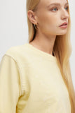 Woman wearing a light yellow top with a plain background