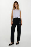 Woman wearing a white sleeveless top and black pants with a star design on a white background