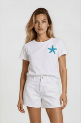 Woman wearing a white t-shirt with a blue starfish design and white shorts on a plain background
