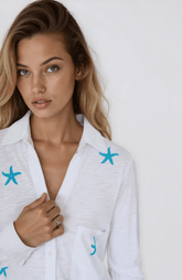 Woman wearing a white shirt with blue starfish designs against a white background