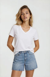 Woman wearing a white t-shirt and denim shorts on a plain background