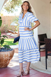 Woman in a blue and white striped dress standing outdoors.