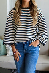 Person wearing a black and white striped sweater and blue jeans indoors.