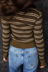 Person seen from behind in fitted brown and cream striped ribbed knit sweater and light blue jeans.