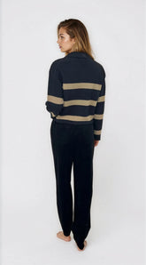 Person wearing a navy sweater with beige stripes and matching pants on a white background
