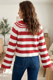 Woman seen from behind in red and white striped knit sweater and blue jeans in bright indoor room.