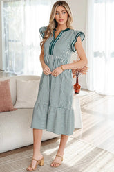 Woman wearing a green and white striped dress in a bright living room.