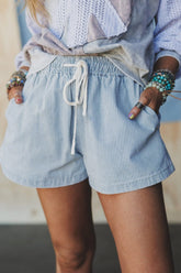 Person wearing light blue striped shorts with a blurred background