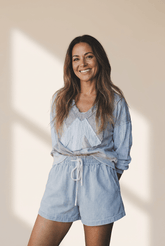 Woman wearing a light blue outfit with a matching top and shorts against a beige background