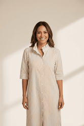 Woman wearing a beige and white striped dress against a neutral background