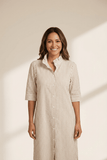 Woman wearing a beige and white striped dress against a neutral background