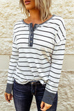 Person wearing a black and white striped long-sleeve shirt against a stone wall.