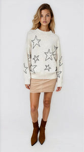 Woman wearing a cream sweater with star patterns on a white background