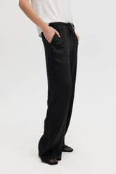 Person wearing black wide-leg pants on a white background