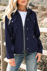 Woman wearing a navy blue jacket with white buttons, standing outdoors.