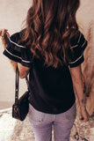 Person wearing a black blouse with white trim and light blue jeans, holding a black handbag.