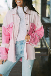 Person wearing a pink and white jacket with light blue jeans outdoors.