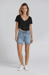 Woman wearing a black top and blue denim shorts on a white background