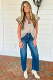 Woman wearing a striped top and blue jeans standing on a brick patio.