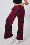 Maroon velvet pants worn by a person on a white background