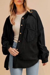 Person wearing a black jacket over a white shirt with a beige background