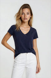 Woman wearing a navy blue t-shirt and white pants on a plain background