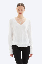 Woman wearing a white long-sleeve top and black pants on a white background