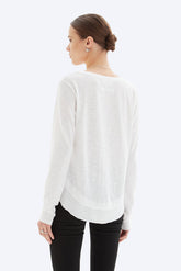 Woman wearing a white sweater and black pants on a white background
