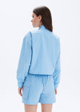 Woman wearing a light blue outfit with a jacket and shorts on a white background