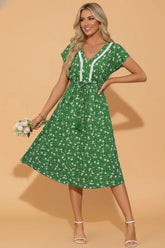 Woman wearing a green floral dress against a beige background