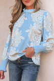 Woman wearing a blue floral long-sleeve top and jeans against a beige background