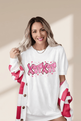 Woman wearing a white shirt with pink designs and text on a beige background