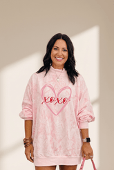 Woman wearing a pink tie-dye sweatshirt with 'xoxo' design on a neutral background