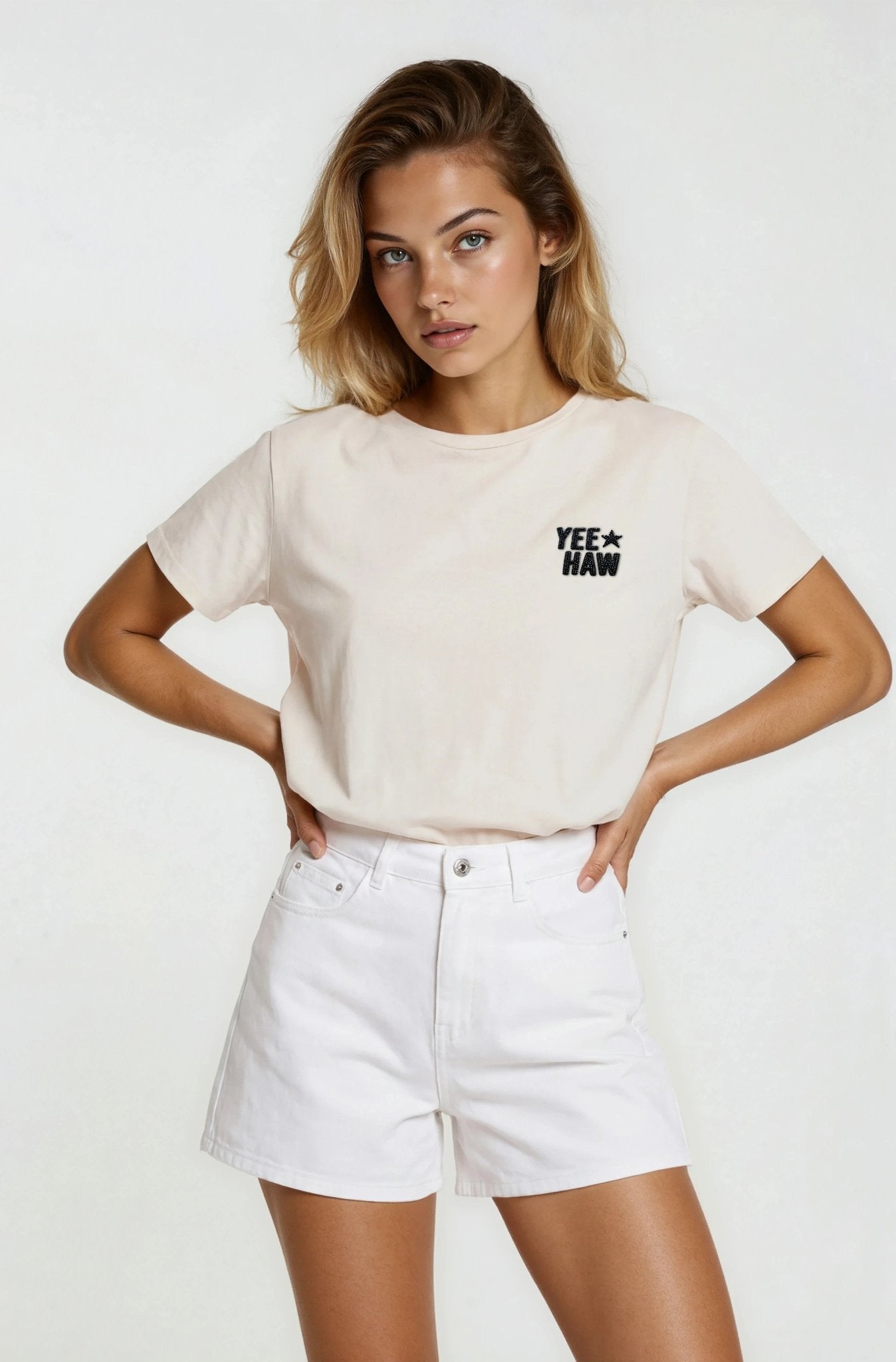 Woman wearing a beige t-shirt with text and white shorts on a white background