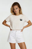 Woman wearing a beige t-shirt with text and white shorts on a white background