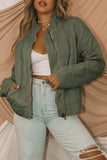 Person wearing a green quilted jacket and light blue jeans against a beige background