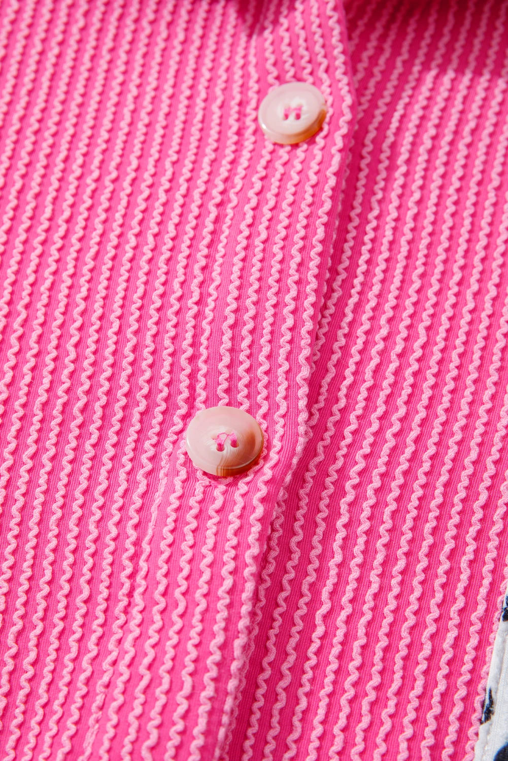 Close-up of a pink textured fabric with buttons.