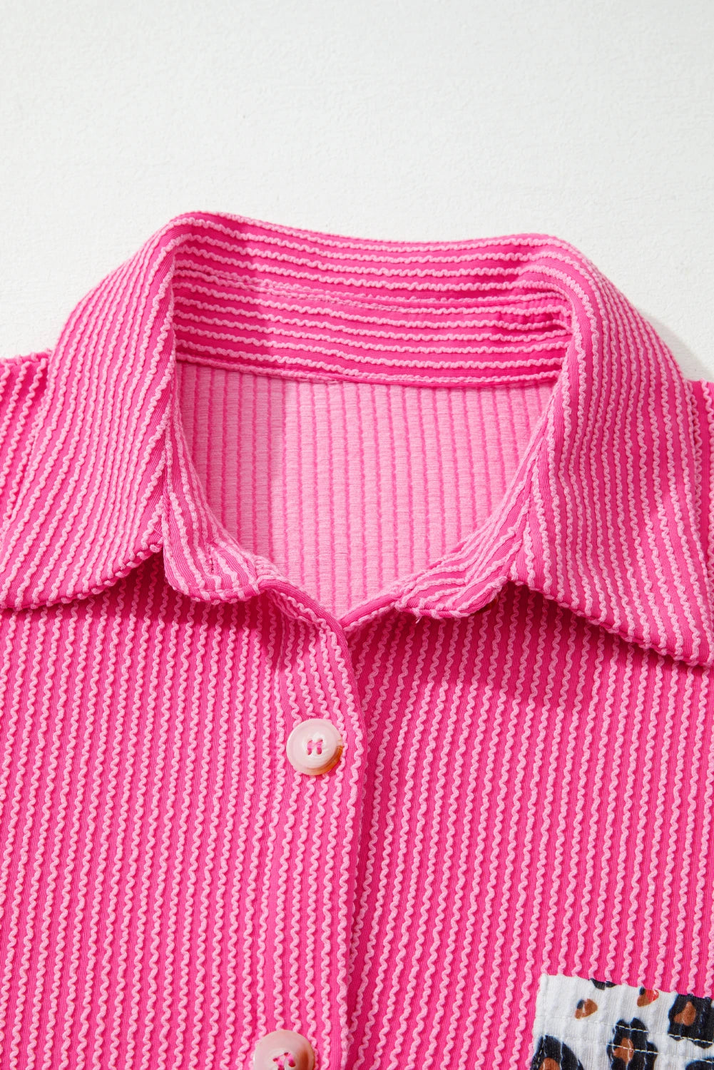 Close-up of a pink textured shirt with a collar on a white background.