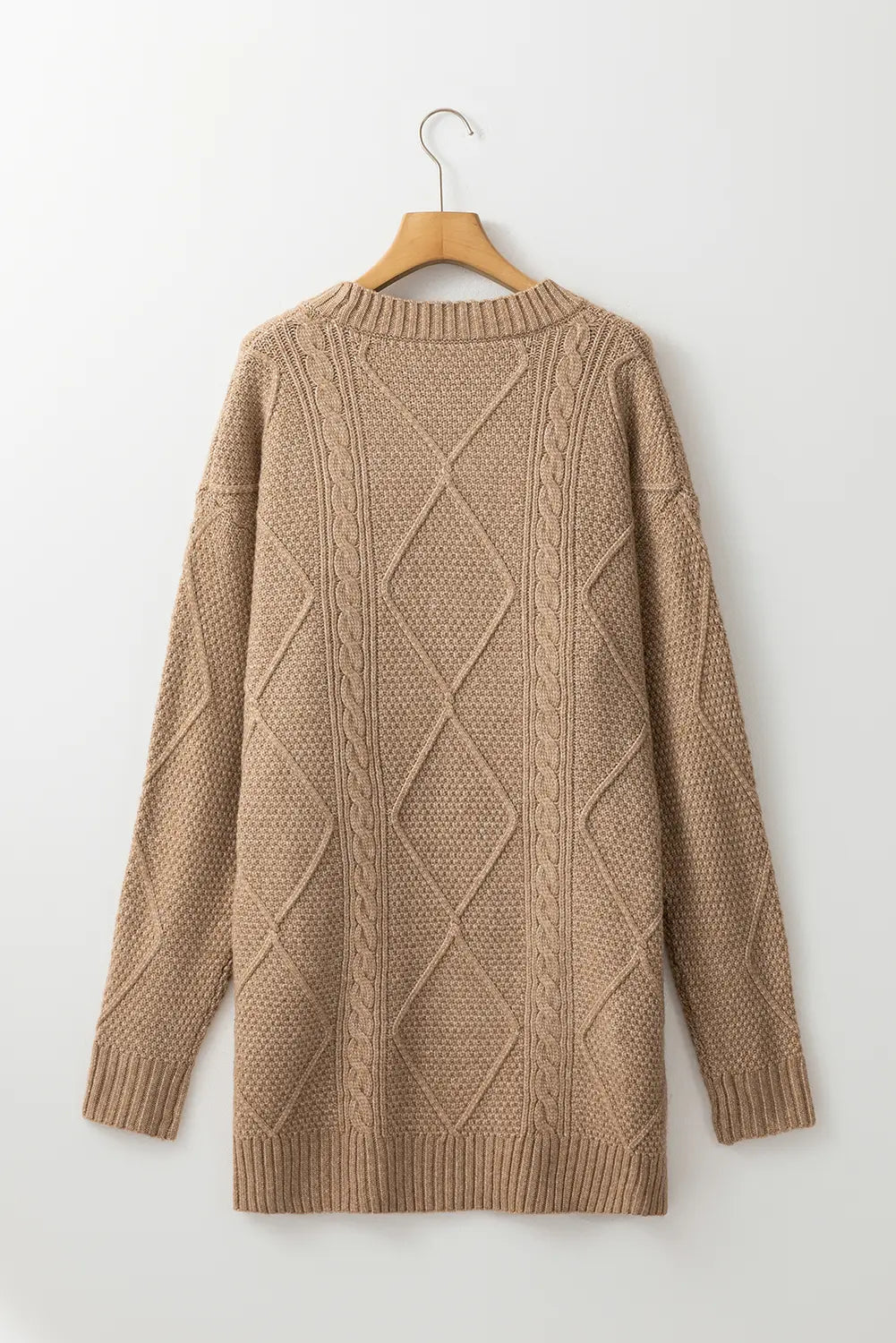 Beige cable knit sweater on a wooden hanger against a white background