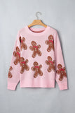 Pink crewneck knit sweater with brown gingerbread men in red scarves on hanger against gray.